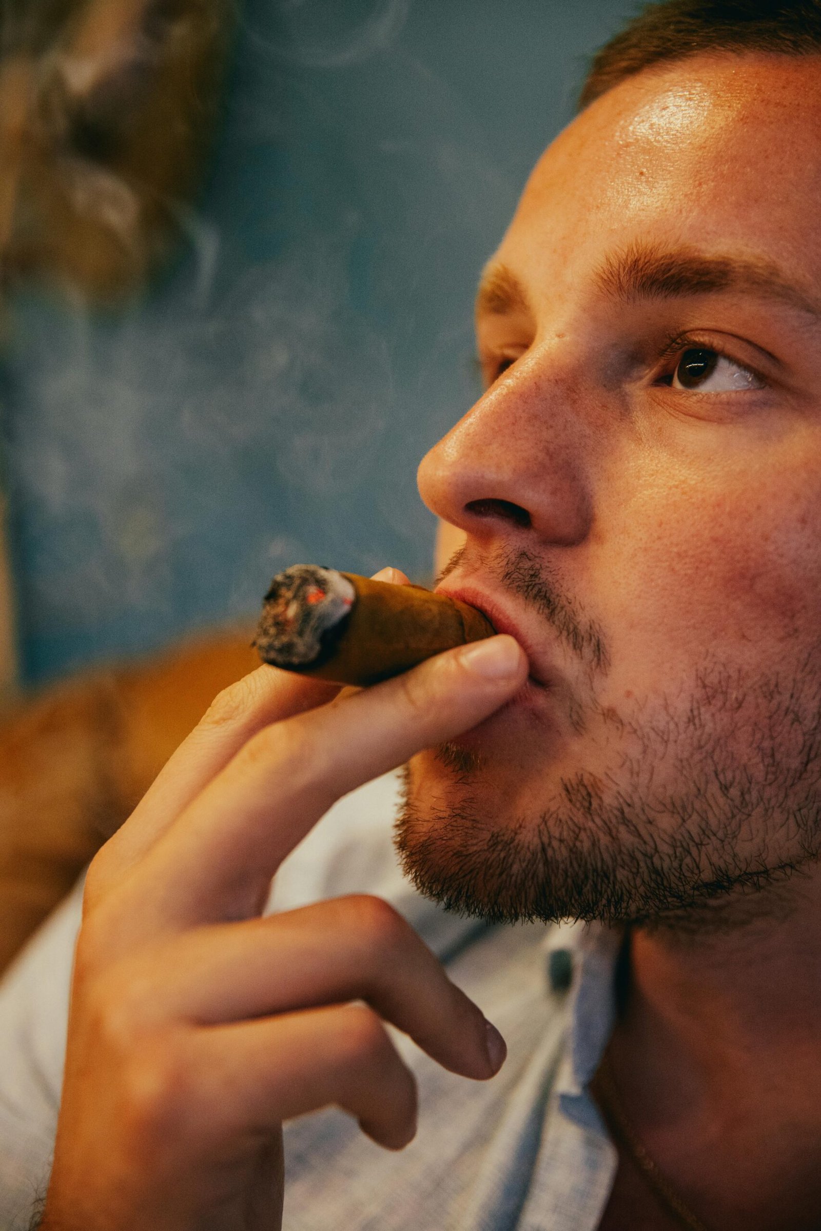 Close-up of a young man enjoying a cigar in a relaxed and thoughtful mood.